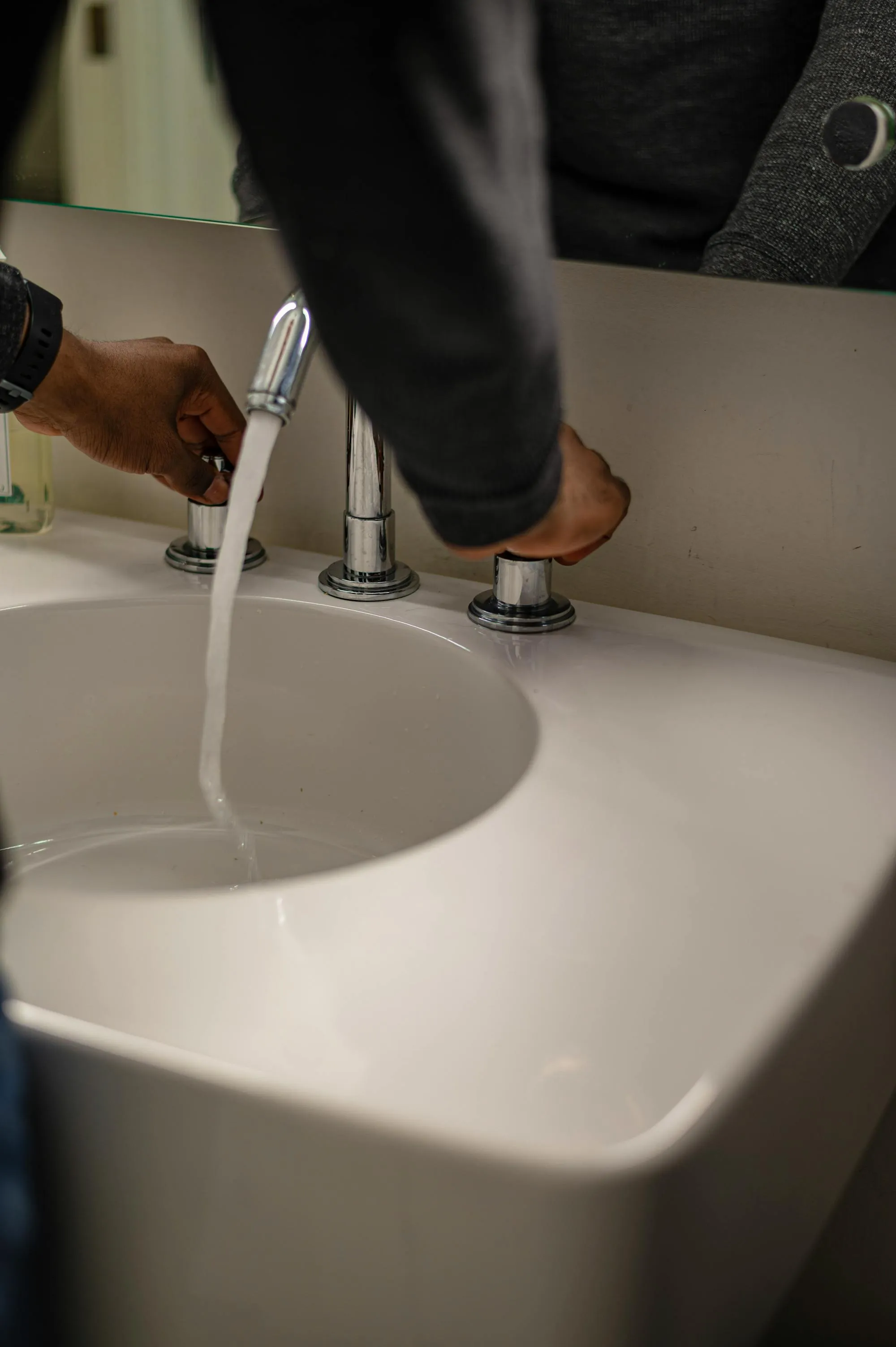 Viktor checking the flow on a chrome basin tap in a Norwich bathroom